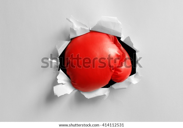 Boxing gloves knockout punch punching\
through torn paper hole ready for message on\
glove