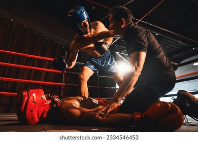 Boxing referee intervene, halting the fight to check fallen competitor after knock out. Intense and fierce boxing match with referee pauses the action for boxer fighter's safety after KO. Impetus - Powered by Shutterstock