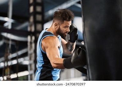 Boxing training. Active guy punching boxing bag at gym, empty space - Powered by Shutterstock