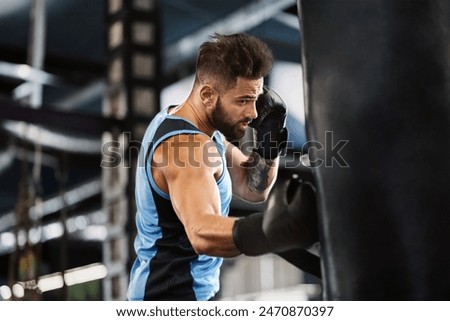 Boxing training. Active guy punching boxing bag at gym, empty space