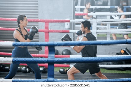 Boxing, training and exercising with a healthy, fit and active female boxer and her male coach or personal trainer in the gym. Workout, fitness and exercise with an athlete and her sports instructor - Powered by Shutterstock