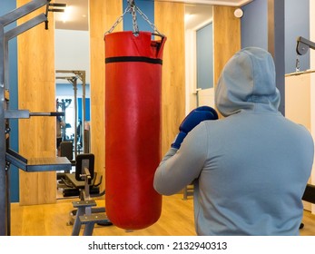 Boxing Training - A Hand And A Red Punching Bag.a Guy In A Hood Hits A Punching Bag