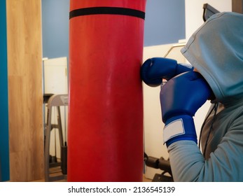 Boxing Training - A Hand And A Red Punching Bag.a Guy In A Hood Hits A Punching Bag