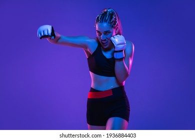 Boxing. Young woman athletic female MMA fighter training isolated on gradient blue-pink background in neon light. Concept of sport, competition, action, healthy lifestyle. Copy space for ad. - Powered by Shutterstock