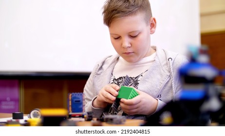 The Boy Of 11 Years, Plays In The Designer From Cubes, Plates, Circuits, Wires. A Small Inventor Creates Robots, Machines From Different Parts Of The Designer. High Quality Photo