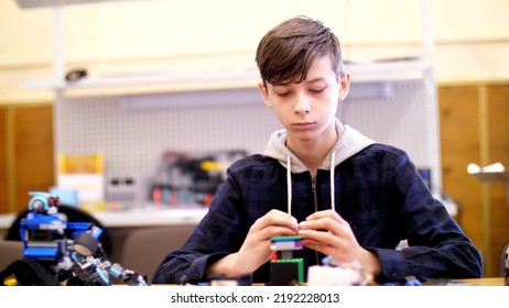 The Boy Of 12 Years, Plays In The Designer From Cubes, Plates, Circuits, Wires. A Small Inventor Creates Robots, Machines From Different Parts Of The Designer. High Quality Photo