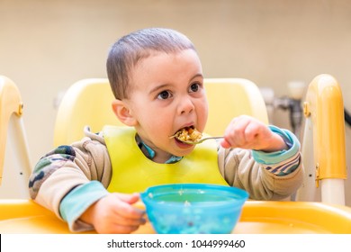 The boy 2 years eats porridge. Children's table. The concept of the child's independence.