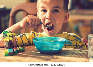 The boy 4 years eats porridge. Children's table. The concept of the child's independence. the boy is breakfasting with an appetite on the kitchen background. toned