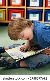Boy (5-6) with Down syndrome reading book in kindergarten