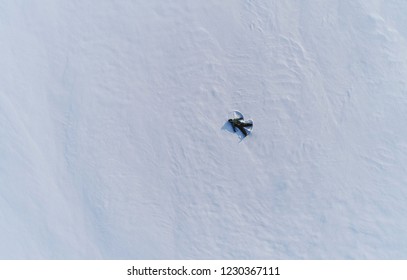 Boy Of 7 Years Makes Snow Angel In Snow Area. Aerial Foto.