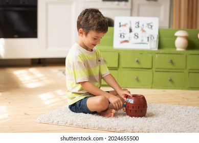 A boy of 7 years old seats on the carpet and plays with toys at home. Educational games for children