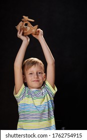 Boy, 8 Years Old, With A Wooden Plane Plays On A Black Background
