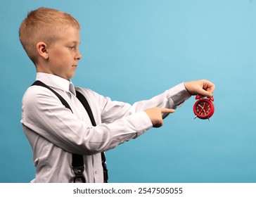 A boy of 9-10 years old in a white shirt holds a red watch in his hands. Advertising space - Powered by Shutterstock