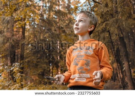 Boy admires beauty of autumn forest. He's holding toy airplane. copy space.