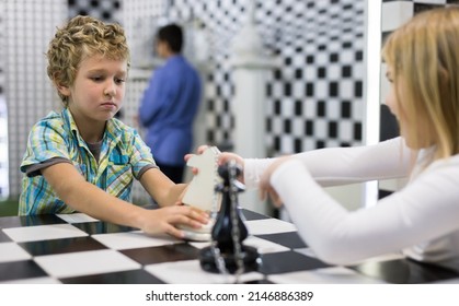 Boy adn girl solving puzzle together in quest room stylized like chessboard