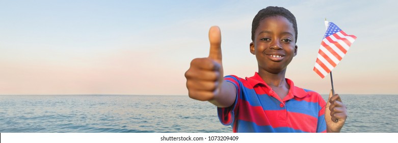 Boy with american flag giving thumbs up against water and evening sky - Powered by Shutterstock