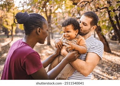 Boy in the arms of his parents in the park - Powered by Shutterstock