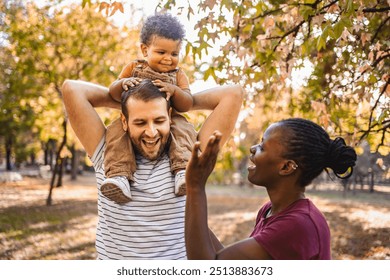 Boy in the arms of his parents in the park - Powered by Shutterstock