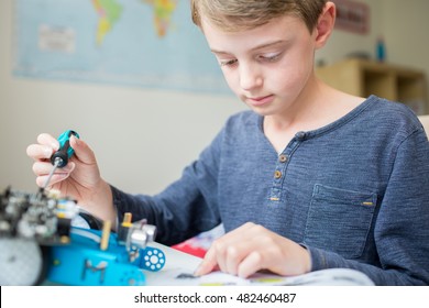 Boy Assembling Robotic Kit In Bedroom