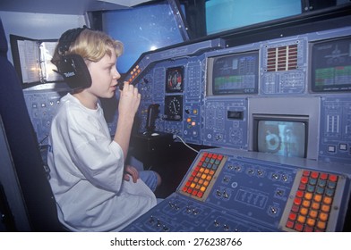 A Boy Attending Space Camp At The George C. Marshall Space Flight Center In Huntsville, Alabama, Sits In The Cockpit Of A Space Shuttle Flight Simulator