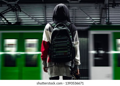 a boy with a backpack inside a train station watching his train go
