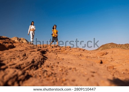 A boy with a backpack and a map walks next to his mother through the desert. Family trekking. Timna National Park. The child is actively spending time. Trekking and hiking.