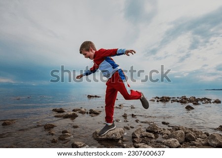 Boy balancing on rock on the lake shore