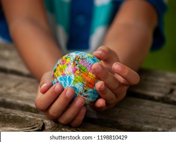 Un niño con una bola del mundo o del planeta Tierra en sus manos. Concepto de ecología