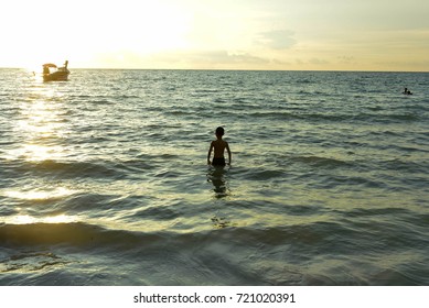 Boy in the beach at sunset.