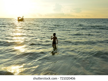 Boy in the beach at sunset.