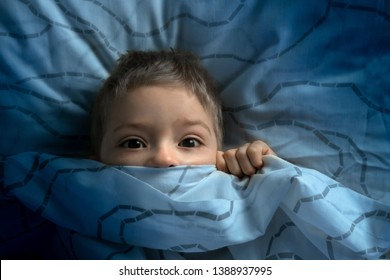 boy in bed with his eyes open. the child is afraid of the dark. tormented by nightmares and terrible dreams in children