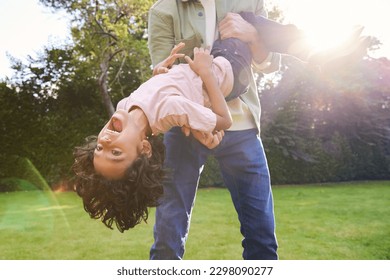 Boy being held upsidedown in garden with mouth open