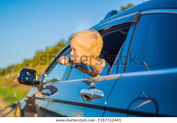 Boy blowing bubbles in the car window. Traveling
by car with children