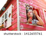 Boy blowing bubbles from a wooden playhouse
