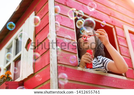 Boy blowing bubbles from a wooden playhouse
