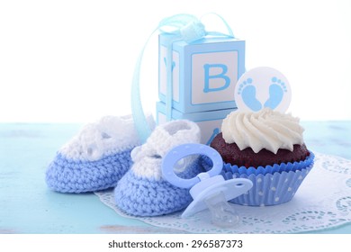 Its a Boy Blue Baby Shower Cupcakes with baby feet toppers and decorations on shabby chic blue wood table. 