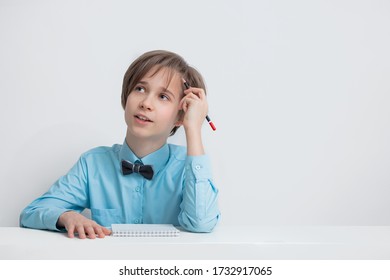 a boy in a blue shirt looks up thoughtfully, a pencil in his hand, writes a plan, an idea, dreams about the future, the concept of study, education, business. Isolate on white background