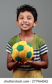 Boy With Body Smeared With Mud Holds A Football And Shows Energy