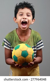 Boy With Body Smeared With Mud Holds A Football And Shows Energy