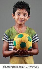 Boy With Body Smeared With Mud Holds A Football 