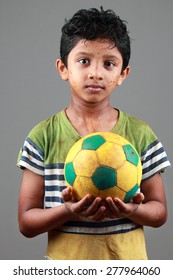 Boy With Body Smeared With Mud Holds A Football 