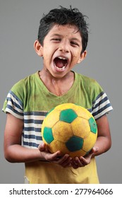 Boy With Body Smeared With Mud Holds A Football And Shows Energy