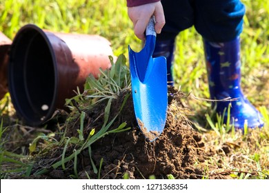 boy in boots digging in the ground with a shovel on Tu Bishvat - Powered by Shutterstock