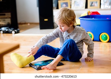 Boy With Broken Leg In Cast Playing On Tablet.