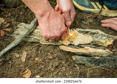 A boy building a fire in a fire-pit made out of rocks and stones- Starting a campfire- Starting a fire using a fire striker- bush craft and primitive skills- firewood and a campsite- flint striker 