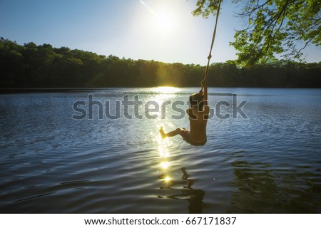 boy bungee jumping over water. kid swings on a rope and ready to jump into the water. Back view. The concept of healthy lifestyle