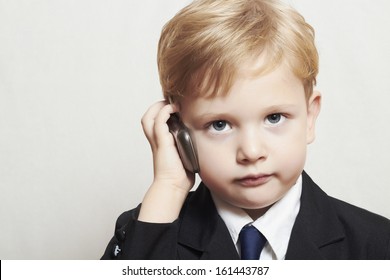 Boy In Business Suit With Cell Phone. Blond Handsome Child. Fashionable Kid