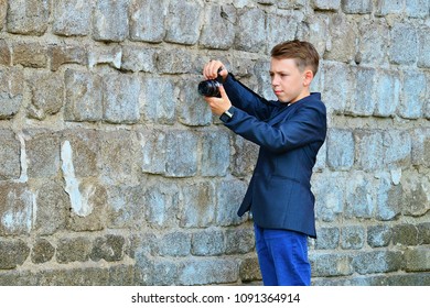 A boy with a camera is engaged in filming and photo shoots on the street are looking at the photo, after the picture.