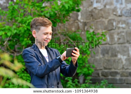 A boy with a camera is writing a message on a smartphone, on the street
