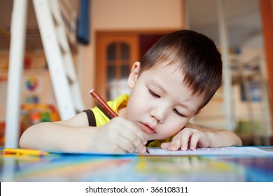 The Boy Carefully And Intently Draws In A Special Notebook For Drawing, Education At Home, Pre-school Training, The Development Of Creative Abilities Of Children. Classroom In The House.